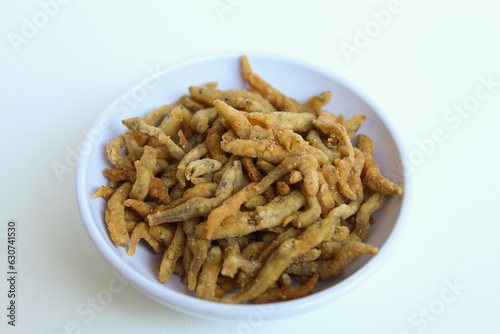Teri crispy, is whitebait or baby anchovy fish or teri nasi in Indonesia, which fried with flour. In a small white bowl. Isolated on white background.