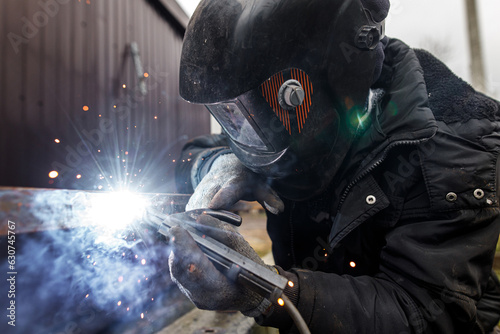 Tableau sur toile Welder man welding metal iron with electrodes, worker wearing protective helmet and gloves