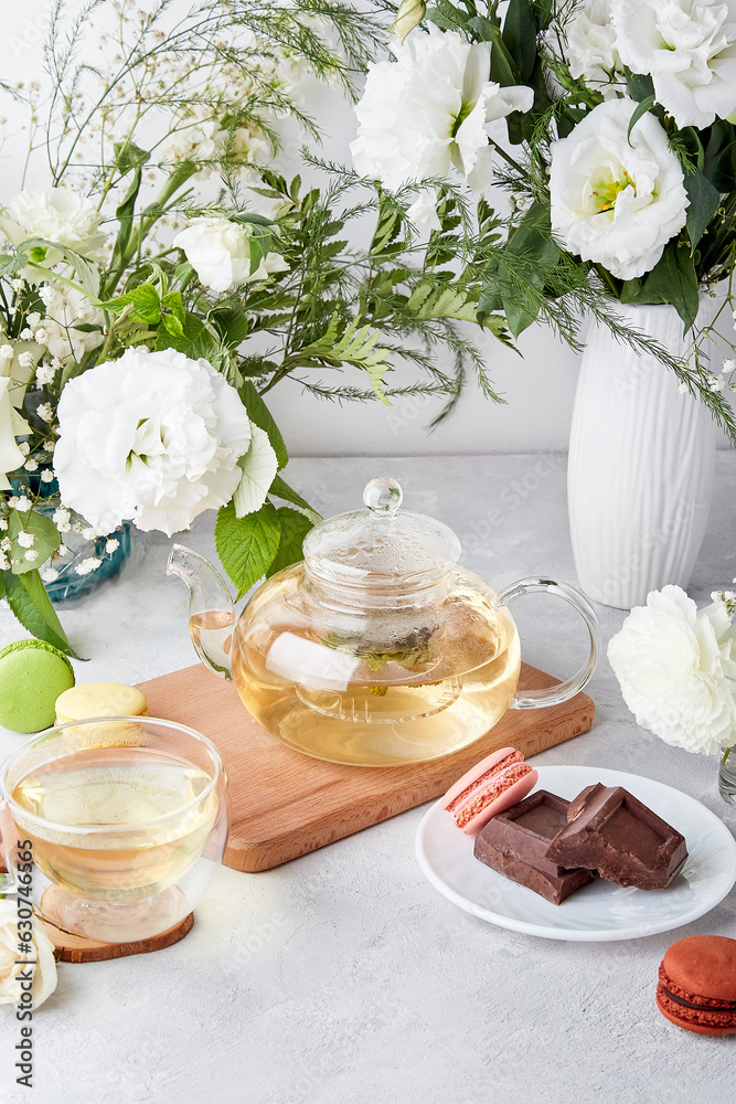 Morning table setting. Green tea, macaroon desserts, chocolate, white flowers - time for yourself, enjoy your time concept