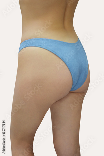 Women's swimming suit. Blue Brazilian bikini bottoms on a slim fit model isolated on white background. Beach women's clothing.