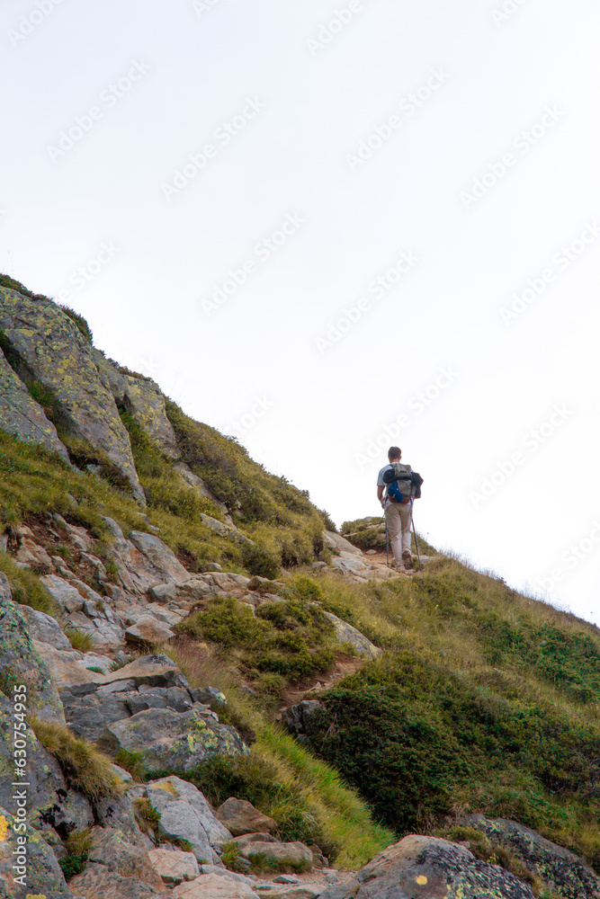 Persona de espaldas andando por sendero en la montaña, cortando con el horizonte