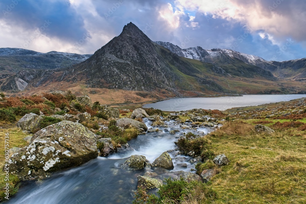 Tranquil mountain stream flows through a lush green meadow in Tryfan mountain, Wales