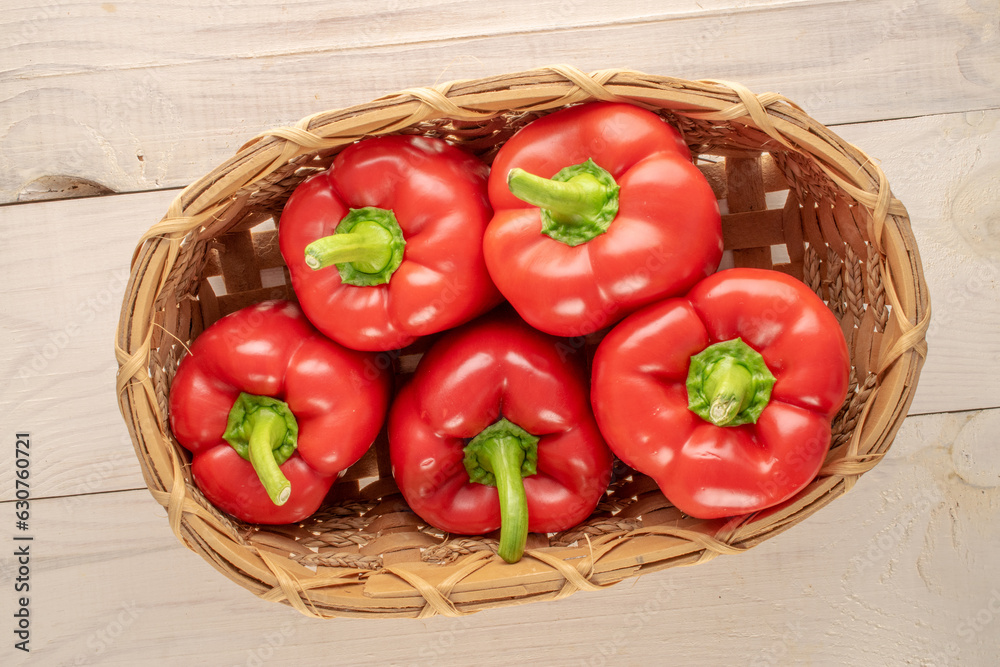 Several sweet red peppers in a basket on a wooden table, macro, top view. Several sweet red peppers in a basket on a wooden table, macro, top view.