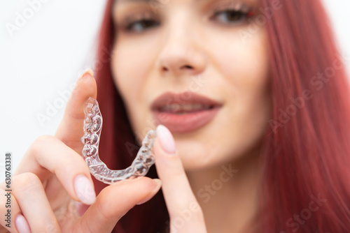 A woman with a beautiful smile holds aligners in her hand