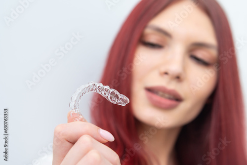 A woman with a beautiful smile holds aligners in her hand photo