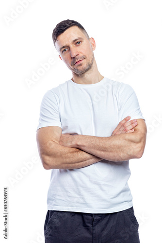 A smiling handsome man in a white t-shirt stands with his arms crossed. Positive attitude and professionalism. Isolated on white background. Vertical.
