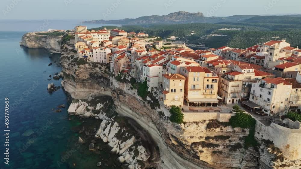 Houses on cliff in the rays of rising sun in Bonifacio old town, Corsica, France. Aerial morning view of Bonifacio, Corsica island. Mediterranean sea