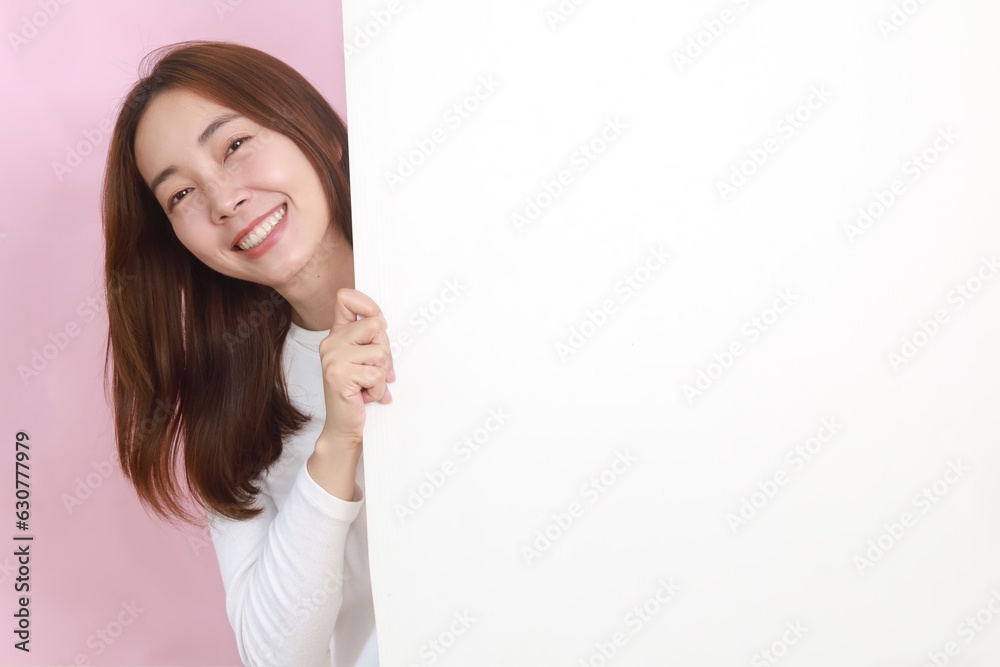 Cheerful Asian woman in casual white shirt behind big blank mock up poster with copy space. Cheerful Asian woman in casual white shirt behind big blank mock up poster with copy space.
