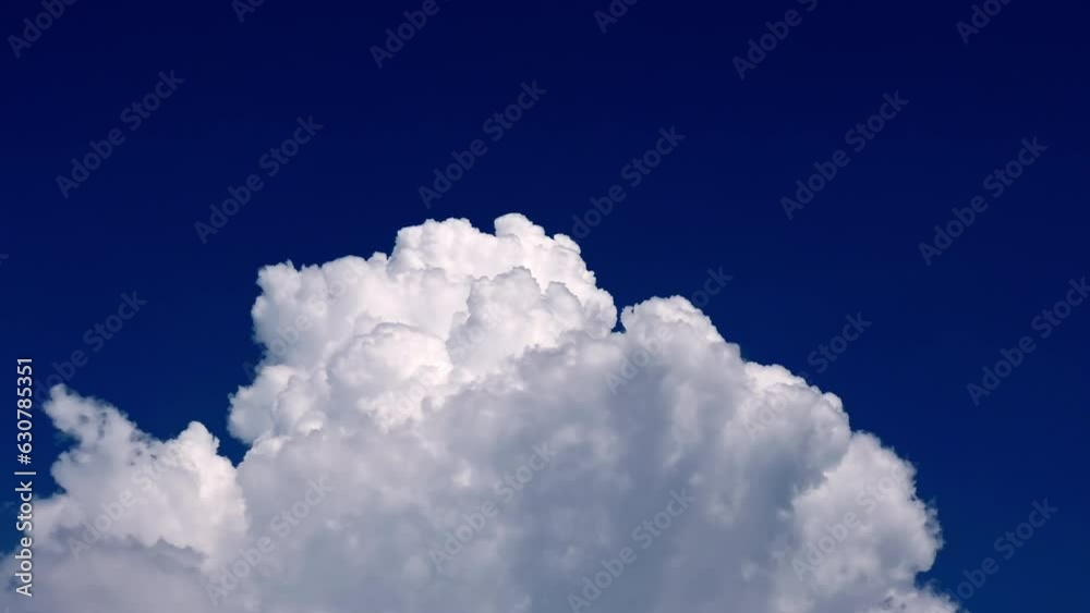 Huge cumulonimbus cloud swelling and rising up hight in the dark blue sky.  Cloudscape, Japan