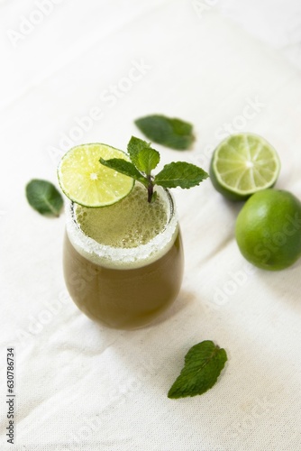 Vibrant cocktail in a small glass garnished with slices of lime and a sprig of mint