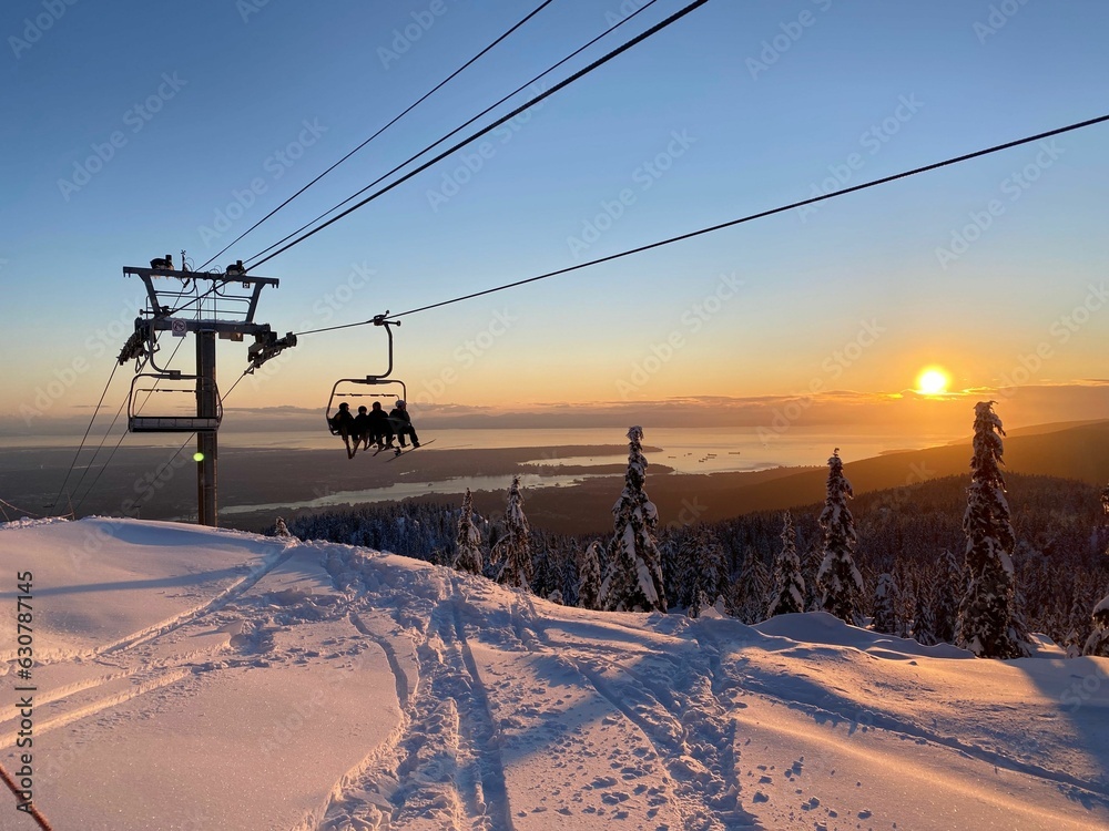 a ski lift that is sitting above the snow hill during sunset