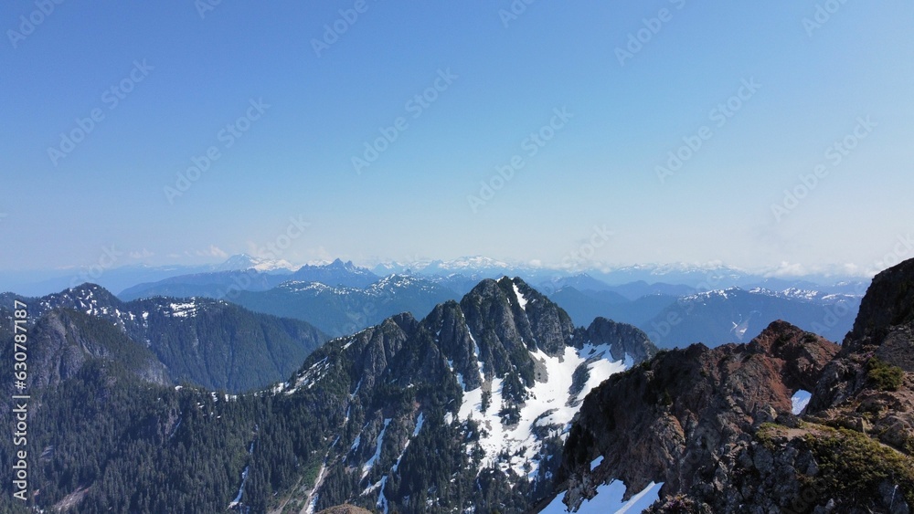 a snowy mountain with some mountains in the background and a clear blue sky
