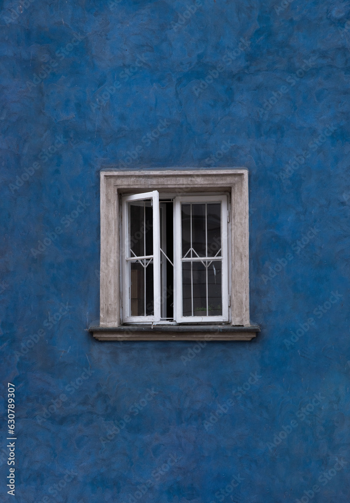 Opened window frame in old town house with blue walls