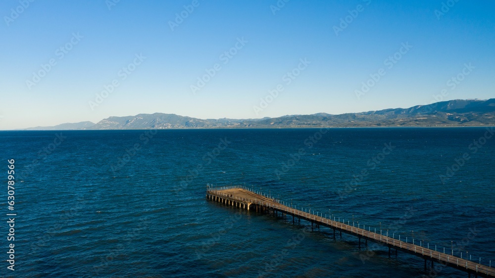Scenic view of a tranquil pier in front of majestic mountains and a crystal blue sky