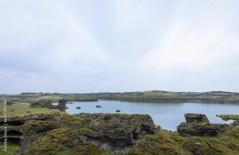 Body of water surrounded by rocks and grass, Lake Myvatn, in the north of Iceland