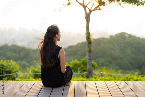 Woman sit on the deck and look at the scenery on the mountain