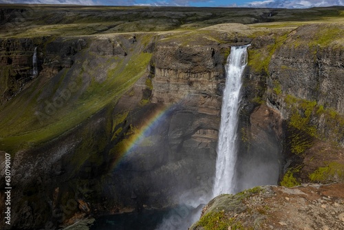 Scenic landscape featuring the Haifoss waterfall cascading over a rocky hillside