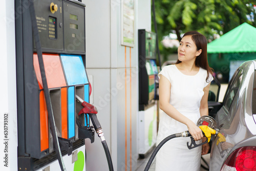 Happy Asian woman refueling a vehicle gas at gas station, self-service at gas station concept.