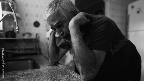 Dramatic senior in despair struggling with mental illness at home in monochrome, black and white. Older person suffering alone in desperation