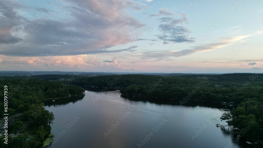 Aerial view of a landscape of a lake and green trees at sunset