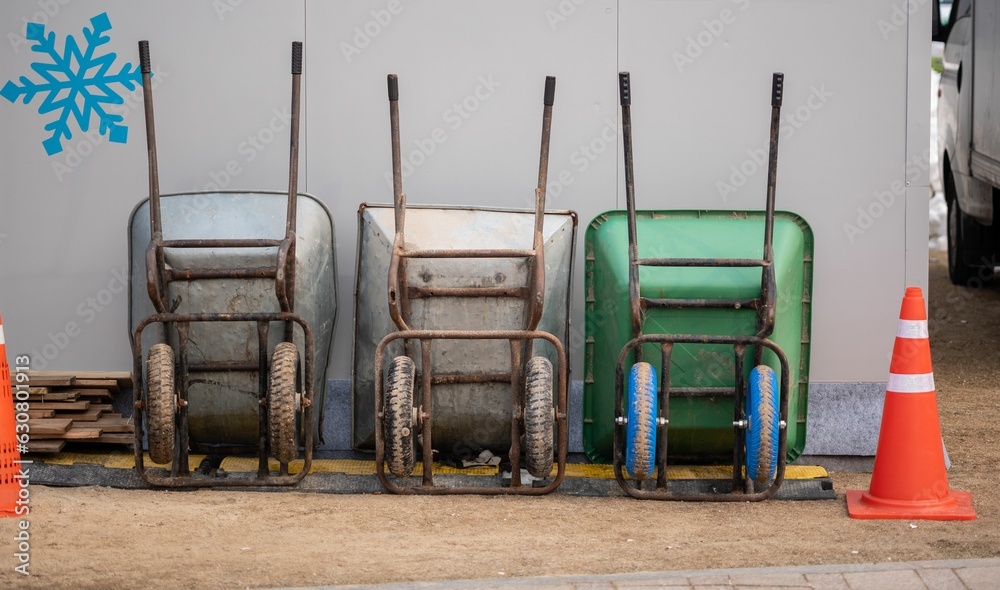 Three wheelbarrows against a white wall with a blue snowflake picture. Three wheelbarrows against a white wall with a blue snowflake picture.