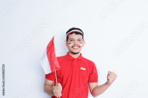 Indonesian man clenched fist, carrying red and white flag, showing excitement when celebrating independence day
