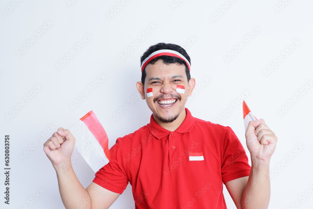 Indonesian man clenched fist, carrying red and white flag, showing excitement when celebrating independence day Indonesian man clenched fist, carrying red and white flag, showing excitement when celebrating independence day