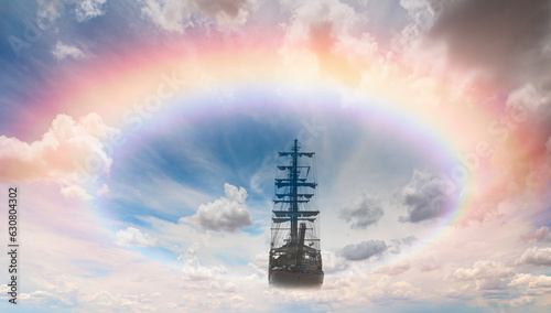 Flying old ship in the stormy dark clouds with rainbow