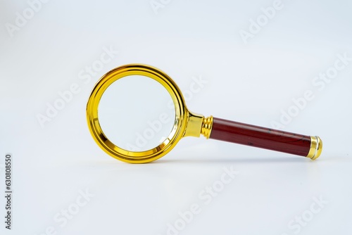 a gold magnifying glass on a white table with wood handle