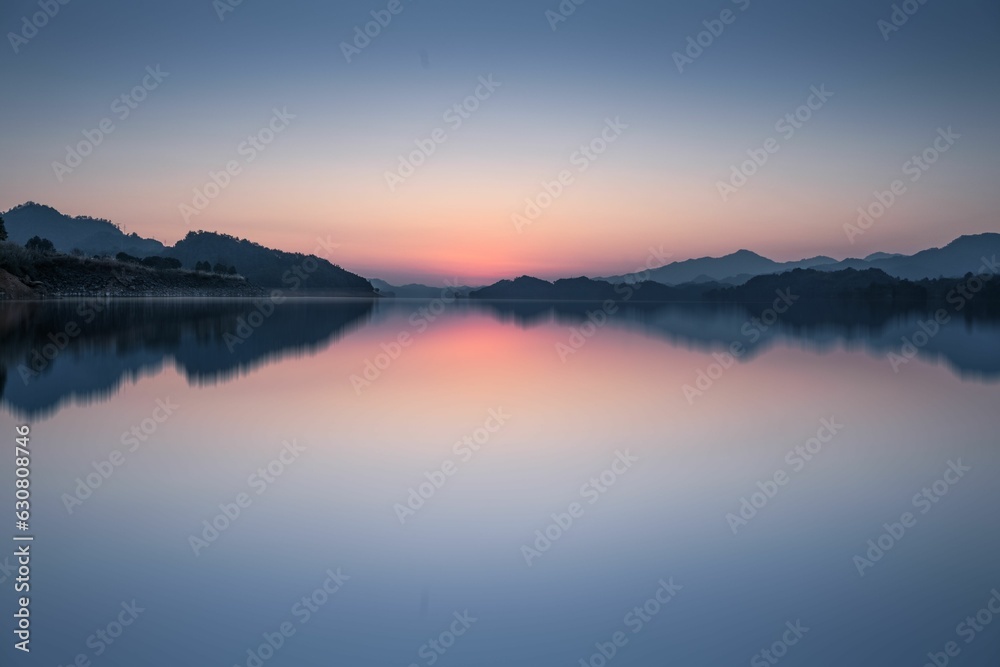 a lake with a mountain and a sunset in the background