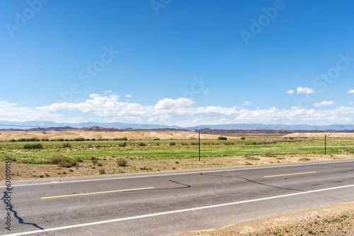 a paved road with no traffic on it under a bright blue sky