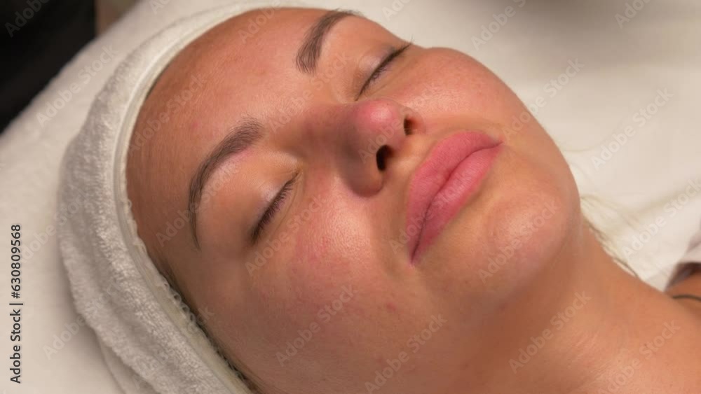 The cosmetologist cleans the face of a beautiful caucasian woman with special disks before applying a mask, peeling, scrub. Facial skin care procedures in a beauty salon The cosmetologist cleans the face of a beautiful caucasian woman with special disks before applying a mask, peeling, scrub. Facial skin care procedures in a beauty salon