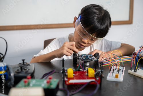 Teenage students build learning with robotic vehicles at desks in STEM engineering science education classes.