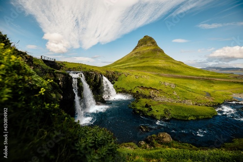 Tranquil Kirkjufell waterfall cascading surrounded by lush mountain terrain in Iceland