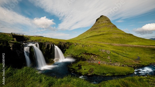 Tranquil Kirkjufell waterfall cascading surrounded by lush mountain terrain in Iceland