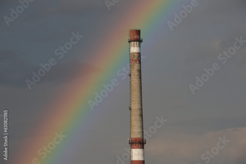 Industrial pipe on the background of blue thick clouds. Rainbow after rain