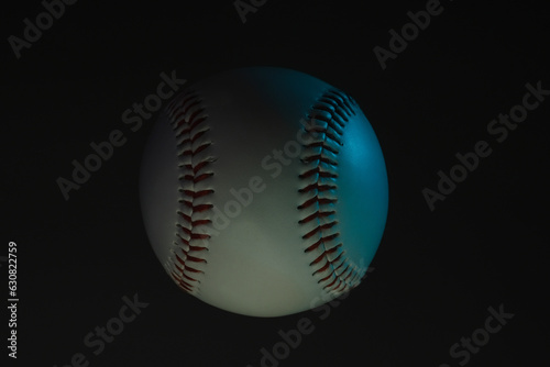 Dark moody lighting with blue tint over baseball ball closeup.