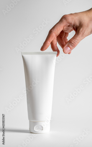 Hand touching big cream tube, cosmetic product mock up, blank package for beauty body moisturizer gel, mask