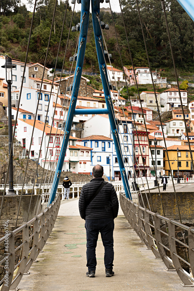 Hombre observando el pueblo de Cudillero en Asturias desde un puente, España.	