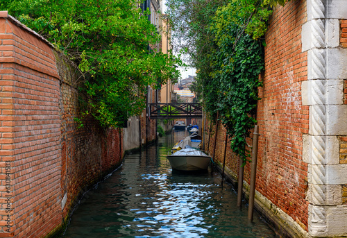 Narrow canal with boats and bridge in Venice, Italy. Architecture and landmark of Venice. Cozy cityscape of Venice.