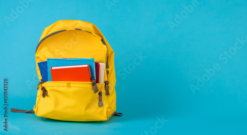 open school yellow bag with books on blue background photo