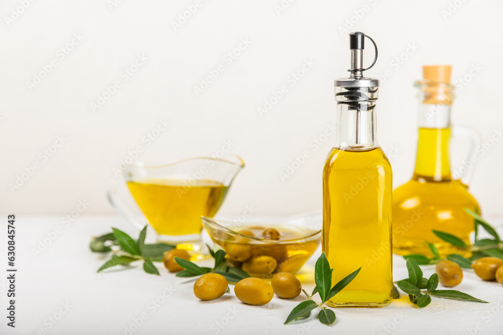 Olive oil in a bottle and gravy boat on the kitchen table. Oil bottle with branches and fruits of olives. Place for text. copy space. vegetable oil and salad dressing. Olive oil in a bottle and gravy boat on the kitchen table. Oil bottle with branches and fruits of olives. Place for text. copy space. vegetable oil and salad dressing.