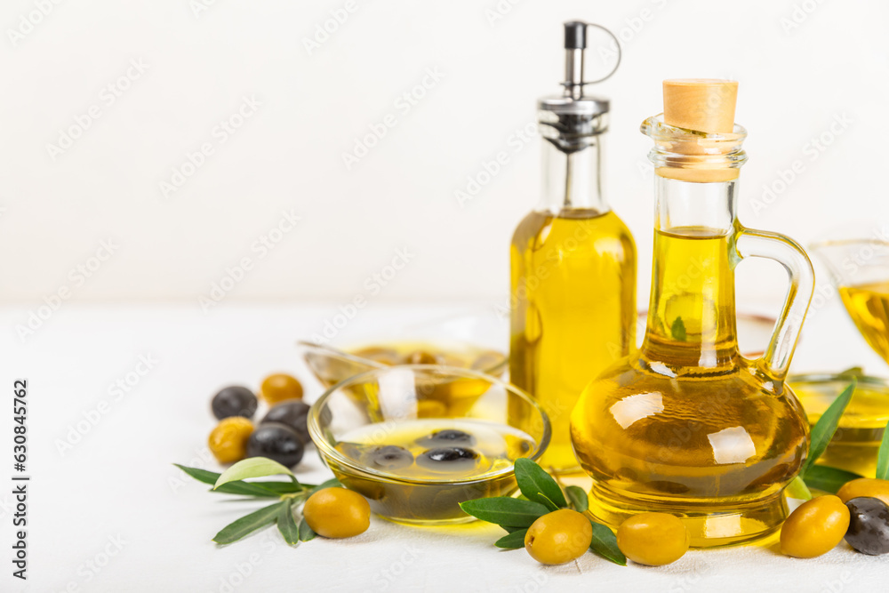 Olive oil in a bottle and gravy boat on the kitchen table. Oil bottle with branches and fruits of olives. Place for text. copy space. vegetable oil and salad dressing. Olive oil in a bottle and gravy boat on the kitchen table. Oil bottle with branches and fruits of olives. Place for text. copy space. vegetable oil and salad dressing.