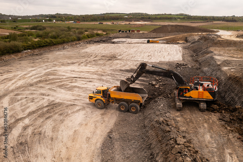 Aerial view above a digger loading a dumper truck on a brownfield site in the construction industry photo