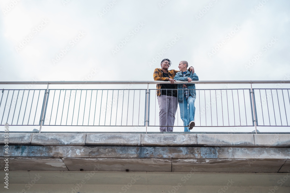 Young lgtbi couple embracing on top of the bridge. Concept: pride, rainbow, friendship