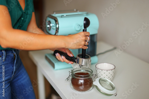 Close-up image of woman hand using blue coffee machine when making big mug of coffee at home