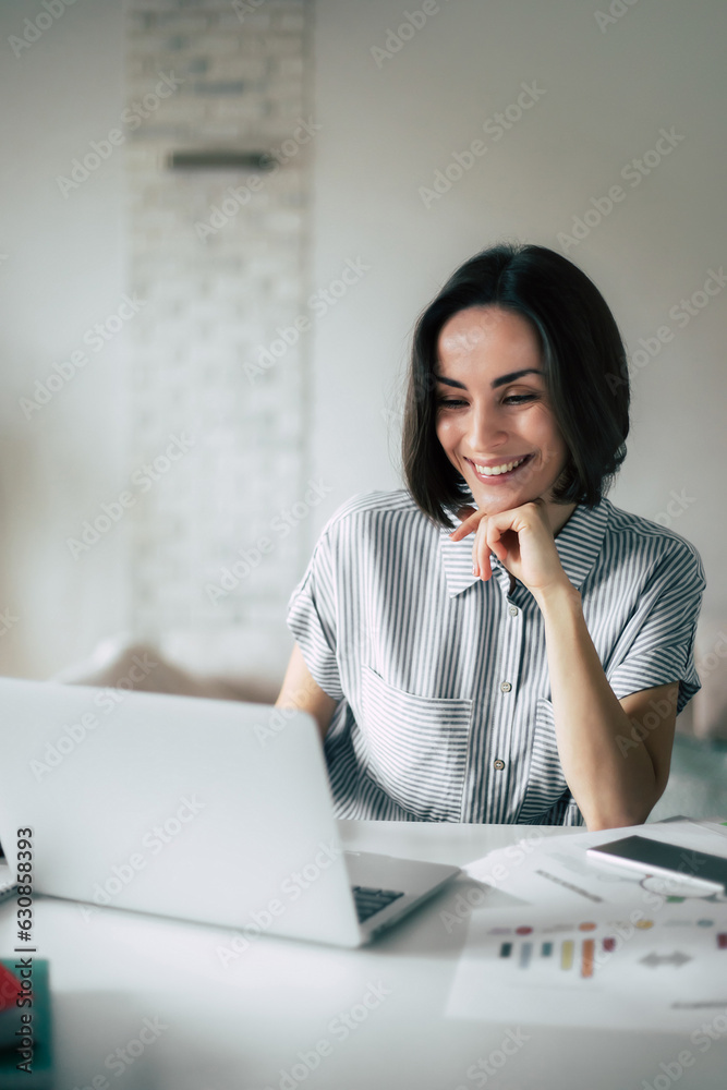Office at home. Freelancer. Cute modern young woman in casual clothing using laptop while working at domestic room. Office at home. Freelancer. Cute modern young woman in casual clothing using laptop while working at domestic room.