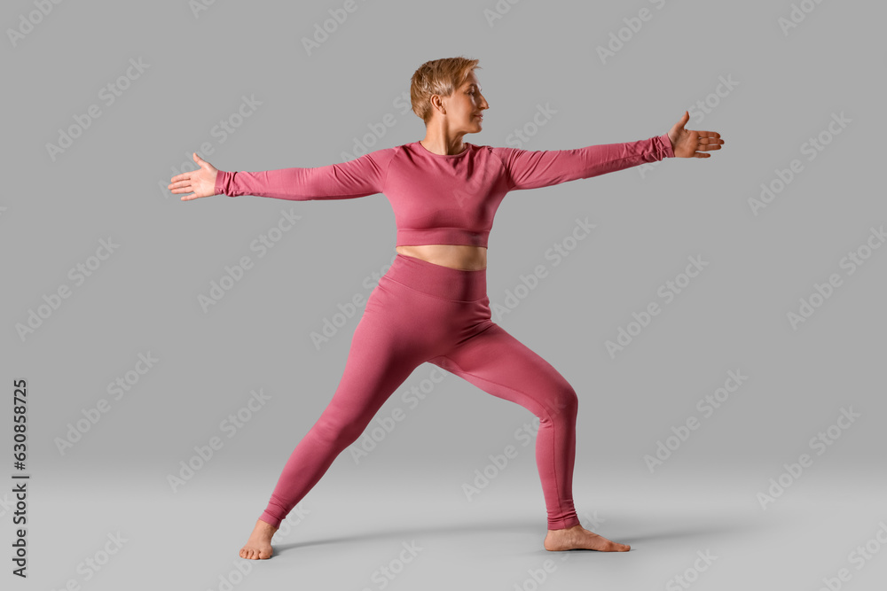 Fototapeta premium Sporty mature woman practicing yoga on grey background