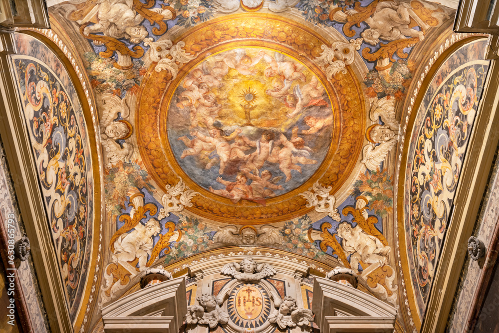 NAPLES, ITALY - APRIL 19, 2023: The ceiling fresco of Eucharist among the angels in St. Francis Borgia chapel in the church Chiesa del Jesu Vecchio by  unknonw artist from 17. cent.