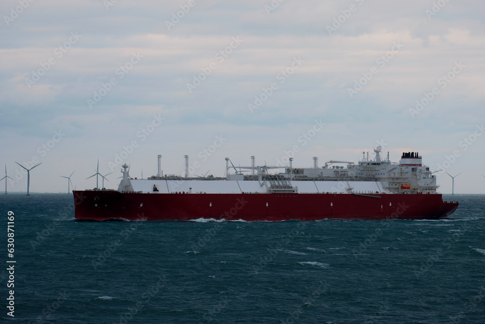 A very large gas carrier is underway with a wind park in the background. LNG tanker. Fully loaded gas tanker.